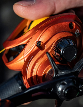 Close-up of an orange low profile baitcasting fishing reel with a blurred background